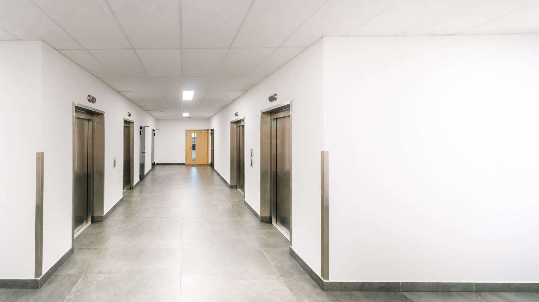 Multiple elevator doors arranged along a clean commercial corridor