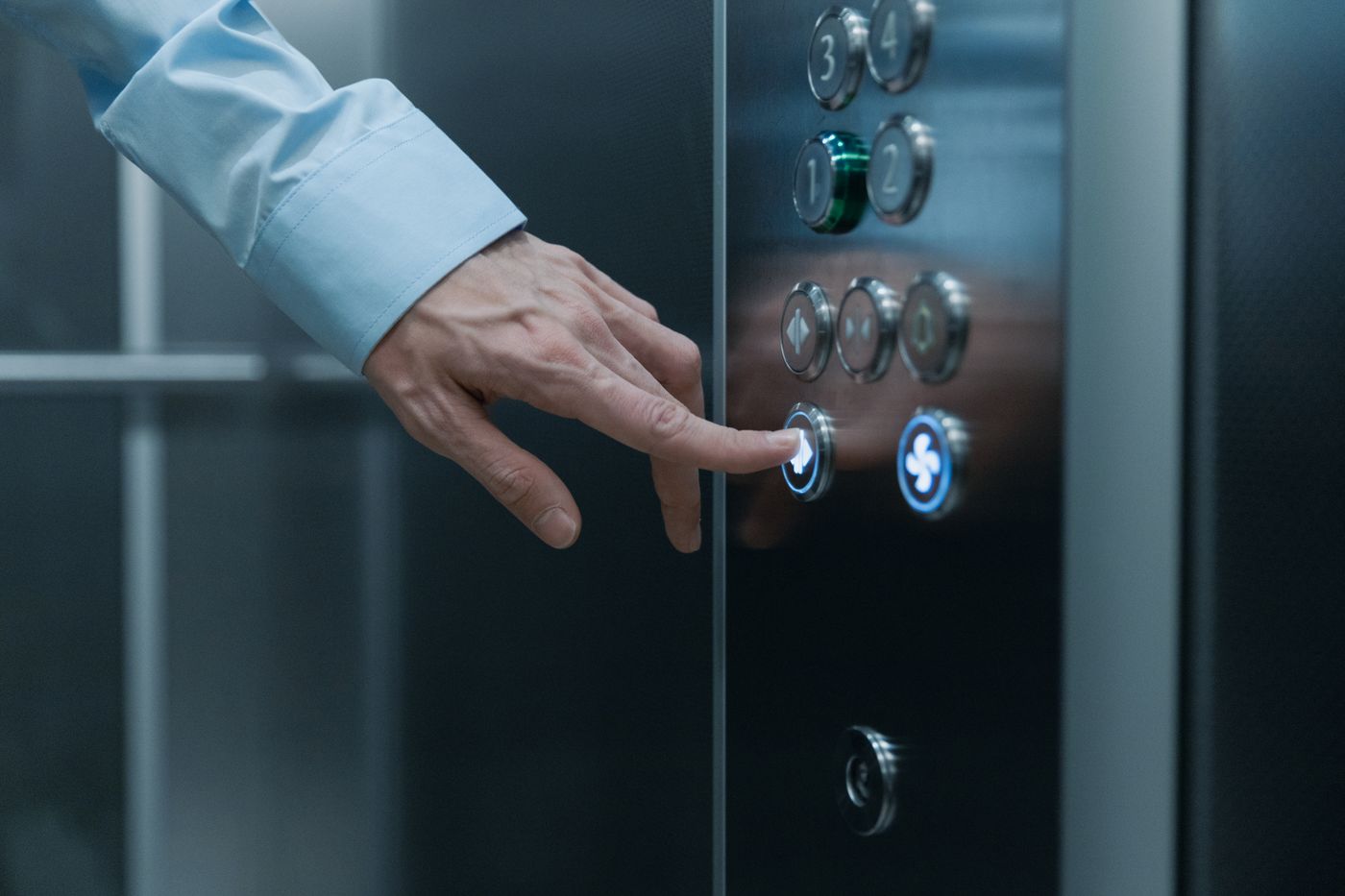 A passenger selecting a floor on a modern elevator control panel